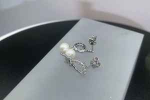 Macro detail of asymmetric S925 sterling silver earrings with freshwater pearls and pave zircons