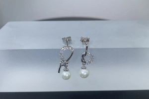 Detail of asymmetric S925 silver earrings with freshwater pearls and sparkling zircons