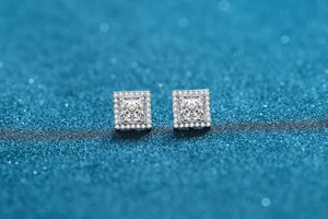 Makrofoto von 925 Silber Halo-Ohrsteckern mit Moissanit auf blauem Glitzerhintergrund