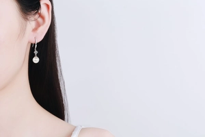 Close-up of 8mm freshwater pearl earrings with moissanite accents on elegant silver hooks