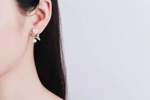 Detail of mermaid tail earrings with freshwater pearls and moissanite on a model