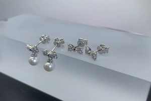 Macro shot of S925 sterling silver bow earrings with round freshwater pearls and moissanite