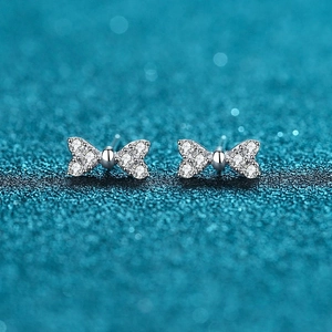 Sparkling S925 silver bow stud earrings with white cubic zirconia on teal background