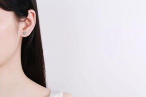 Close-up of 925 sterling silver clover earrings with sparkling moissanite petals on model