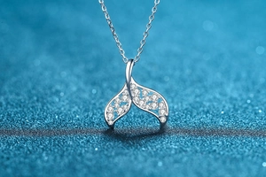 Macro shot of silver mermaid tail pendant with shimmering crystals on blue starry background