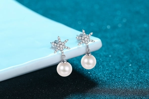Detailed view of silver snowflake earrings featuring round white freshwater pearls