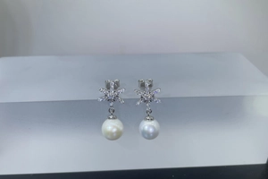 Detail of snowflake silver earrings featuring sparkly stones and white freshwater pearls