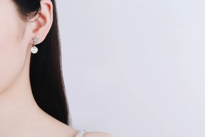 Close-up of S925 sterling silver snowflake earrings with freshwater pearls on model ear