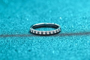 Detail of S925 silver half-eternity ring with square-set moissanite on blue background