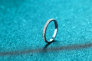 Macro detail of S925 sterling silver half-band moissanite ring on a glitter background