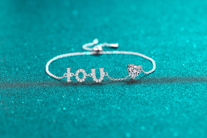 Vue macro du bracelet cœur en argent S925 avec breloques lettres IOU en diamant