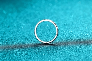 Close-up of a S925 silver ring with vertical grooves on a sparkling teal background