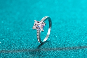 Macro shot of emerald cut moissanite ring with radiant pavé diamond setting