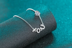 Détail d'un bracelet en argent S925 avec pierre en cœur et breloques lettrage YOU
