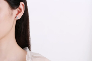 Close-up of S925 sterling silver triangle stud earrings with shiny zircons on a model