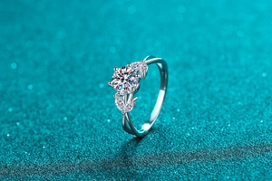 Detailed side view of 1 carat moissanite ring with leaf-shaped side stones on blue background