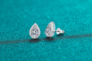 Detailed macro view of S925 sterling silver pear cut moissanite stud earrings on blue texture