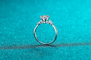 Macro view of a 1 carat round moissanite ring with pear-shaped side stones in silver