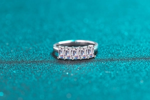 Detail of five emerald-cut transparent gemstones set in a polished S925 silver ring band
