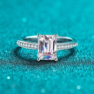 Emerald-cut moissanite ring with four-prong setting and side diamonds on silver band
