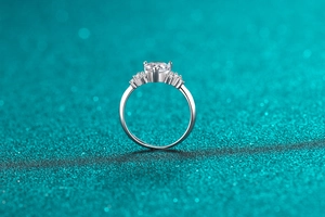 Close-up of heart-shaped moissanite ring with claw setting and side accent stones