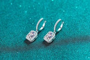 Close-up of S925 silver radiant cut emerald earrings with shimmering halo details
