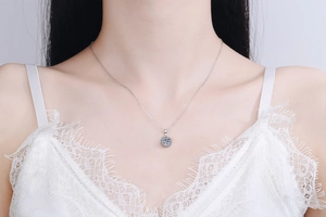 Detailed view of a 925 sterling silver sun flower moissanite pendant on a lace dress