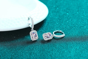 Detail of S925 silver earrings featuring radiant cut emerald and pave moissanite halo