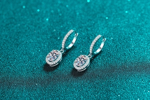 Macro shot of S925 sterling silver oval moissanite earrings with halo setting on teal base