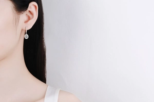 Close-up of S925 sterling silver drop earring with moissanite on a model ear