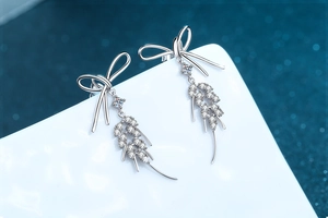 Macro detail of 925 sterling silver bow earrings with sparkling marquise moissanite