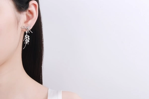 Close-up of 925 silver bow drop earrings with sparkling moissanite stones on a model
