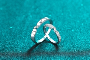 Macro shot of silver moissanite couple rings with geometric engraving on sparkly background