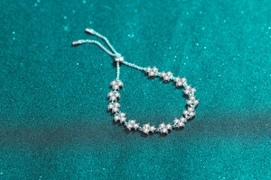 Detailed view of S925 silver four-leaf clover bracelet with sparkling stones on green background