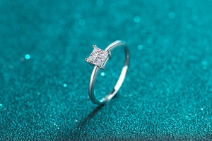 Macro shot of princess cut square moissanite stone in classic four-prong silver setting