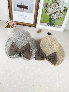 Detailed texture of woven straw sun hats featuring large dark brown decorative bows