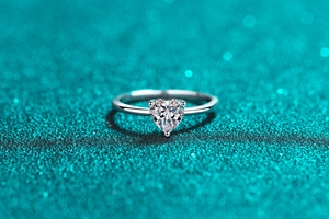 Macro shot of a heart-shaped moissanite ring with a delicate three-prong silver setting