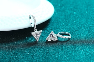Macro shot of S925 silver triangle earrings with sparkling moissanite stones and zircon pavé