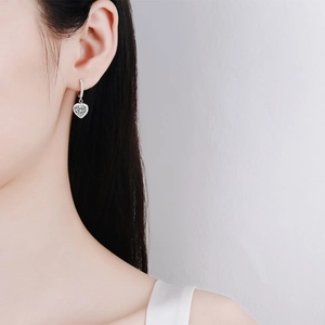 Elegant S925 sterling silver heart-shaped moissanite hoop earrings worn by a model
