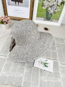Detail of blue and white woven straw sun hat featuring a brown fabric bow accent