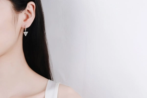 Close-up of a silver triangle Moissanite earring worn by a model in soft light