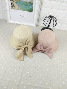 Detail view of handmade woven straw hats with large linen bows in beige and pink tones