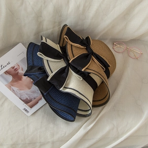 Detailed view of woven straw sun hats with large bow ribbons in various colors