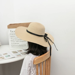 Detail view of khaki children's straw hat featuring a stylish black ribbon bow decoration