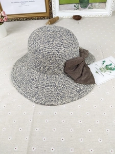 Detail of woven straw sun hat with two-tone texture and large brown fabric bow decoration