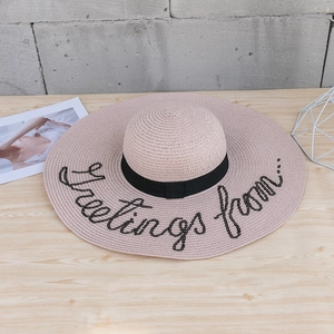 Chapeau de paille rose à large bord avec ruban noir et broderie Greetings From sequins
