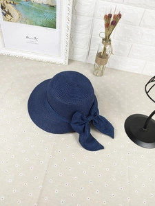 Detail of dark blue straw sun hat featuring a large elegant bow and fine weave texture