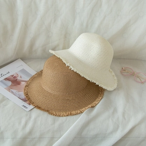 Detail of foldable straw hats with frayed edges in beige and khaki for summer sun protection