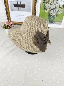 Detailed close-up of straw sun hat with woven texture and decorative brown linen bow