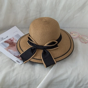 Detail of fine straw sun hat with black bow ribbon on a natural linen background